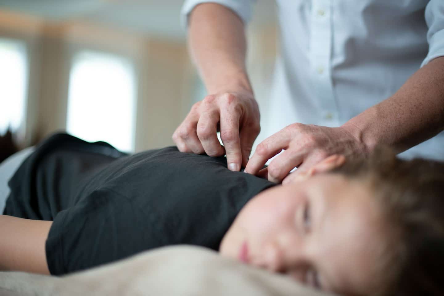 Fizjoterapeuta korygujący górną część pleców i bark pacjenta.