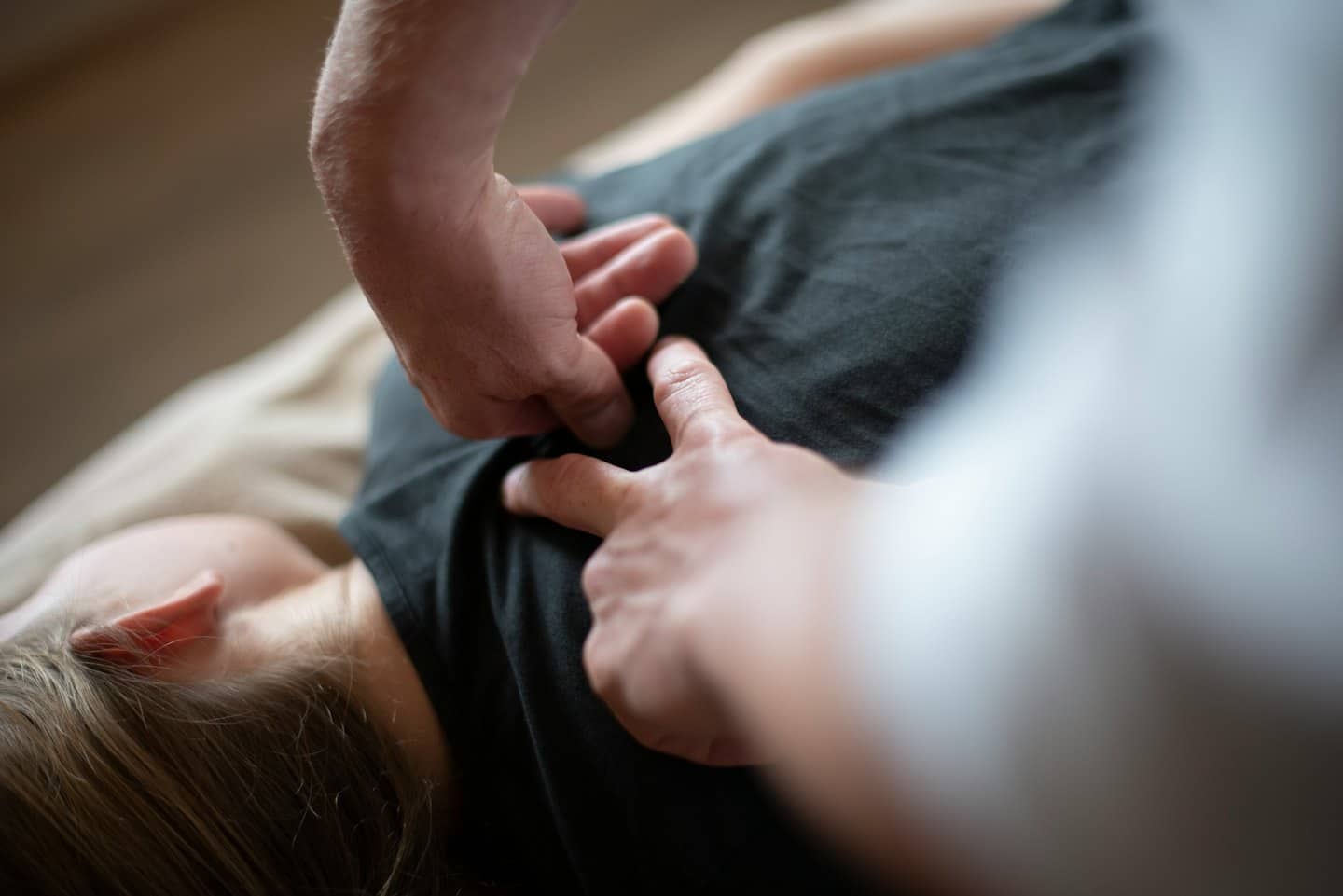 Dłonie wykonujące terapeutyczną korektę górnej części pleców.